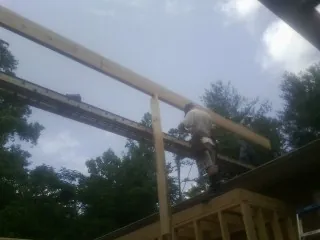 Carpenter setting a ridge beam over a new addition frame — Ice Dam Removal by Roofing Brothers in Neosho