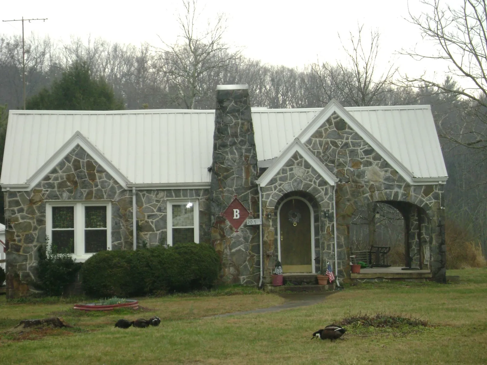 White metal roof on a stone cottage with steep gables in Neosho
