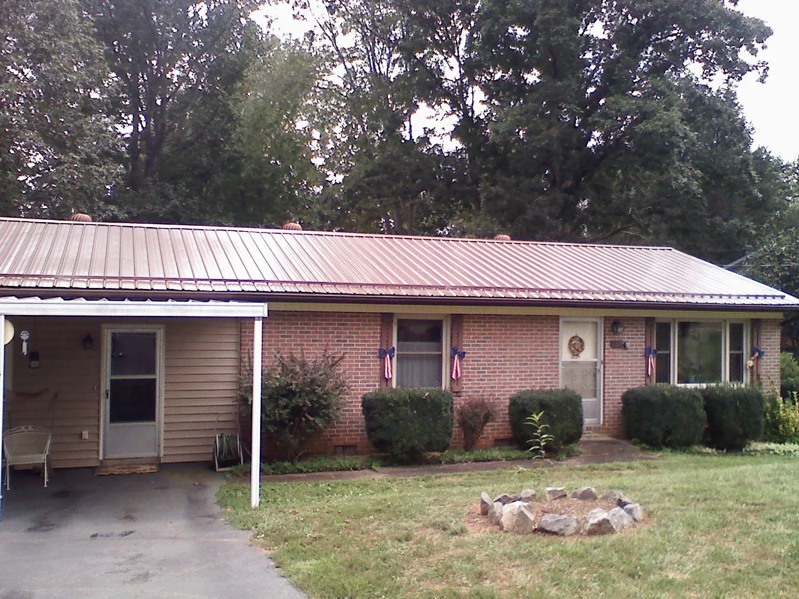 Bronze metal roof and carport on a brick ranch home — Roof Repair work by our crew in Neosho